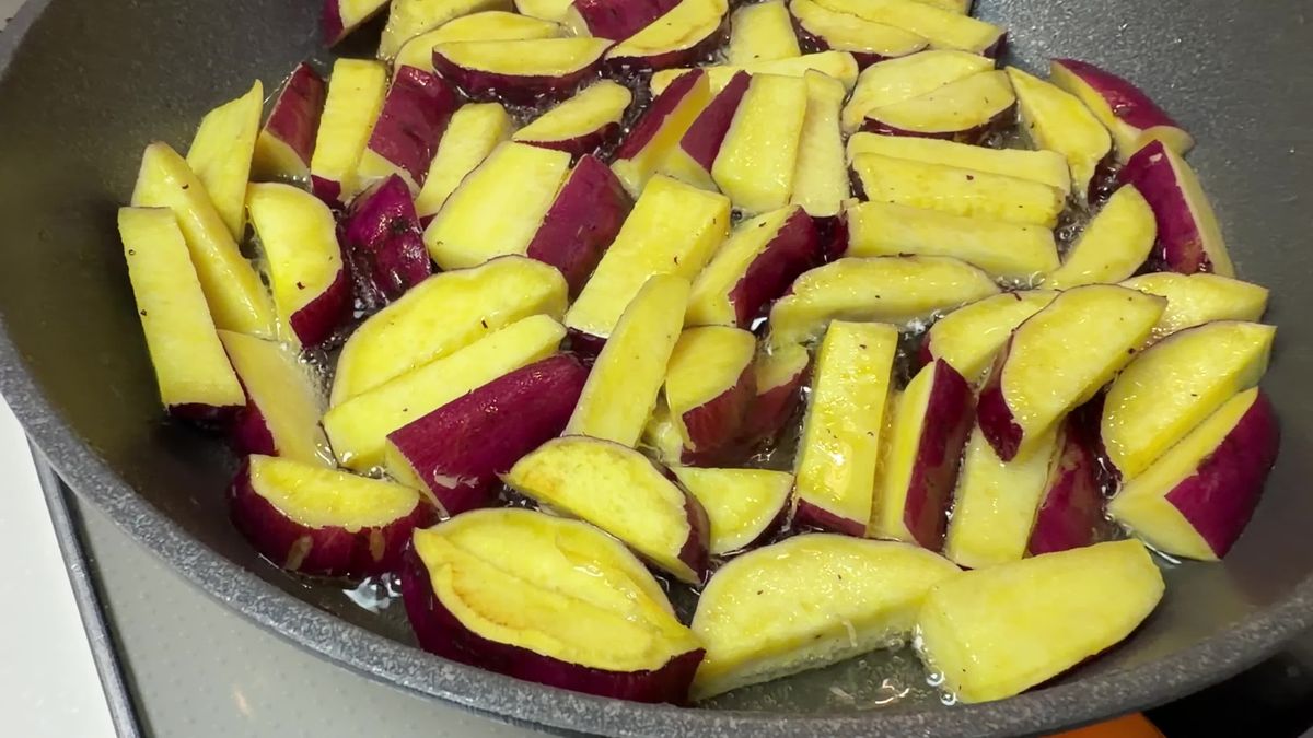 フライパンの少なめの油で、スティック状に切ったさつまいもを揚げ焼きにしているところ