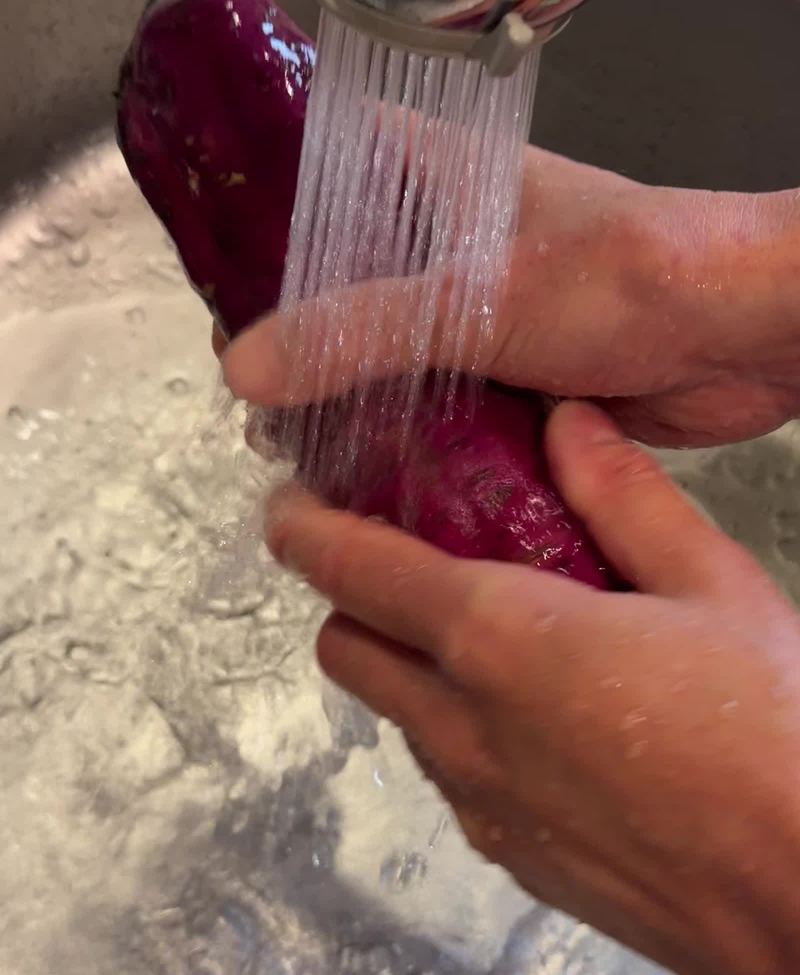 流水をかけながら、手でさつまいもの土を洗い落としているところ